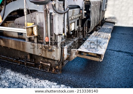 pavement machine laying fresh asphalt or bitumen on top of the gravel base during highway construction or road repairing