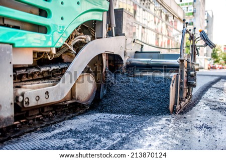 industrial truck laying fresh bitumen and asphalt at road construction site