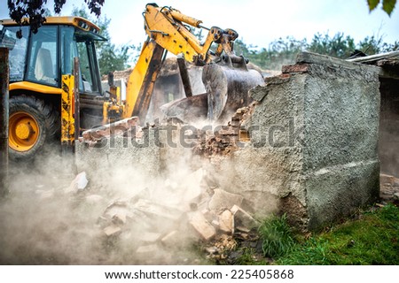 bulldozer demolishing concrete brick walls of small building