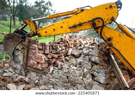 bulldozer on demolition site working on an old building and loading bricks and concrete
