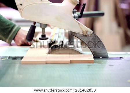 wood factory worker cutting wood boards with sliding compound mitre saw with sharp blade