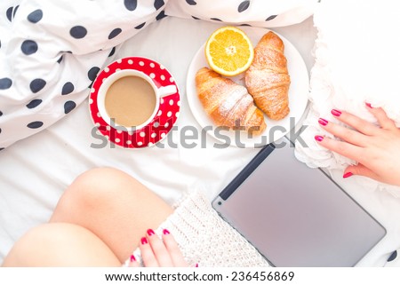 Woman on bed with tablet, breakfast and coffee, relaxing on a sunday morning