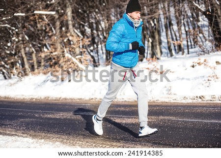 Young athlete going for a run outdoor in snow, hardcore training and jogging