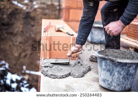 Construction worker using trowel and cement for installing the brickwork
