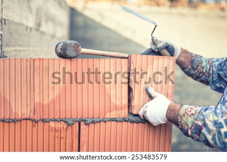 Construction bricklayer worker building walls with  bricks and mortar