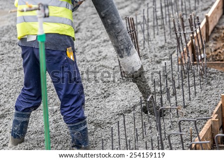 Construction worker pouring concrete, directing the pump tube