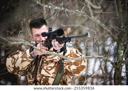 Hunting, army, military concept - sniper holding rifle and aiming at target in the forest during operation