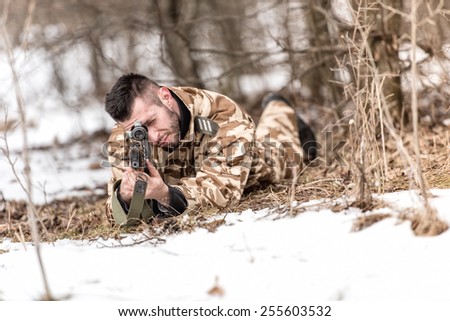 military man in combat uniform holding a gun and shooting outdoors. Hunting or military concept