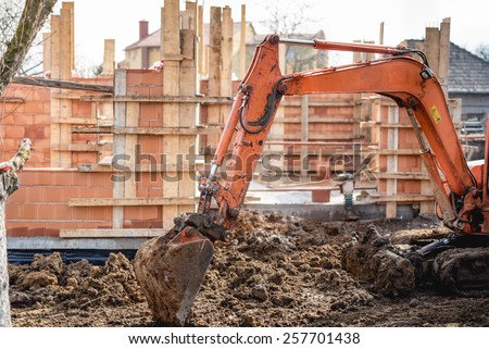 track-type excavator loader working on earth and loading at house construction site