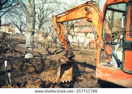 Industrial truck loader excavator leveling earth and ground hole at house construction site. Vintage effect