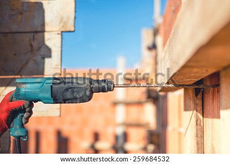 worker on construction site using drilling machine and wire rod at building walls