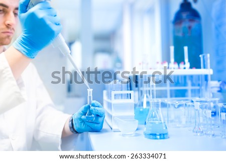 Test tubes in clinic, pharmacy and medical research laboratory with male scientist using pipette