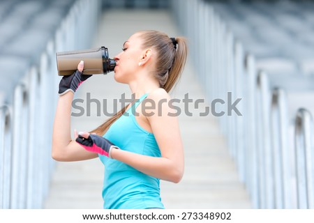 Portrait of healthy fitness girl drinking protein shake. Woman drinking sports nutrition beverage while working out