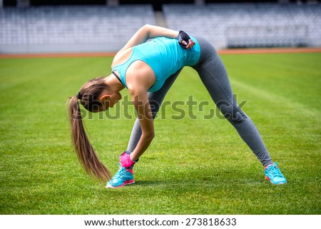 Active female runner stretching and relaxing muscles after hard workout. Fitness and sports concept