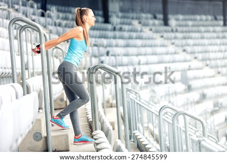 Fitness girl doing fitness exercises and working out on stadium stairs. Jogger on morning training, healthy lifestyle routine concept