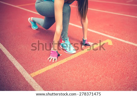 athlete on starting blocks at stadium track preparing for a sprint. Fitness, healthy lifestyle concept