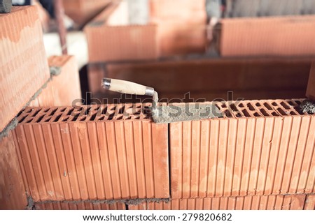 Construction site details and tools, trowel, putty knife on top of brick layer on interior walls