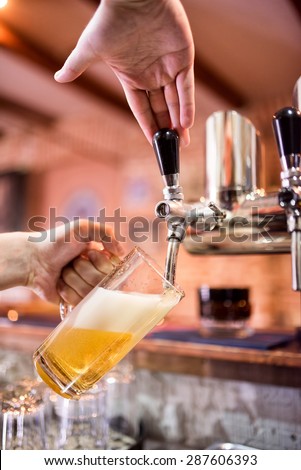 Barman at bistro or pub pouring lager and unfiltered beer in glass
