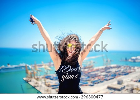 Attractive girl wearing black tank top smiling, laughing and taking pictures with camera phone. Traveling concept with happy woman.
