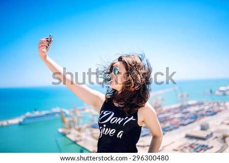 Brunette girl taking pictures of herself, taking selfie with mobile camera, with smart phone. Concept of traveling and modern social media