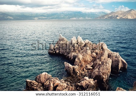 Island cliffs and seascape, aerial view with calm sea and clear sky. Soft, vintage effect on photo