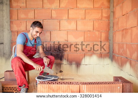 Construction mason worker, bricklayer building brick walls with spatula and mortar