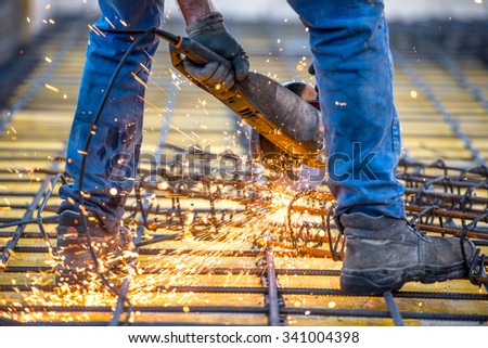 industrial worker cutting steel, sawing reinforced bars using angle grinder mitre saw