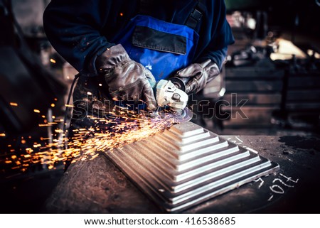 Professional worker using angle grinder for cutting and finishing steel