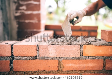 industrial Construction bricklayer worker building walls with bricks, mortar and putty knife