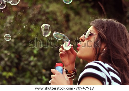 Fashion girl blowing bubbles in the wind