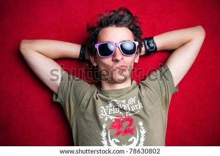 Young model making strange faces on red background, wearing purple sunglasses. isolated