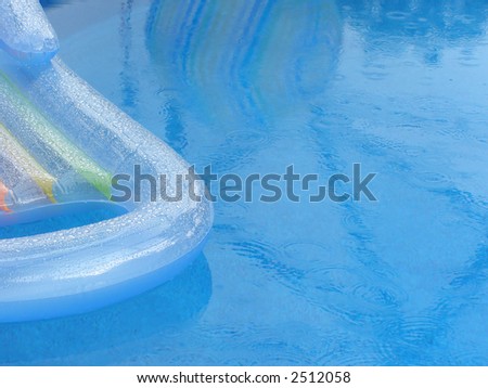 Rainy day at the swimming pool with chaise lounge and reflection of beach ball