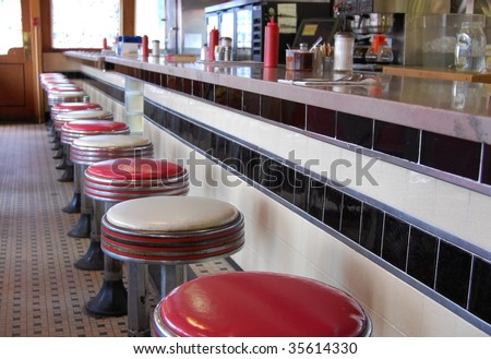 An old-fashioned diner with a tile floor and art deco style bar stools.