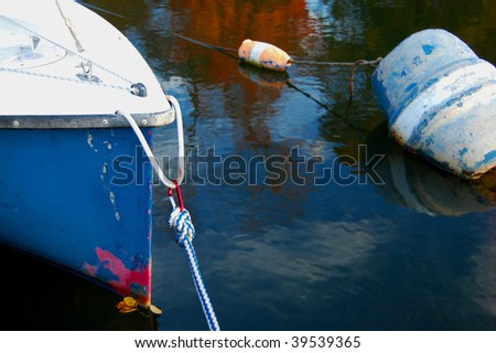 An old sailboat and buoys on a lake with autumn foliage reflected on the surface