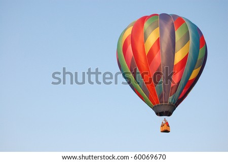 A rainbow colored hot-air balloon in the sky on a beautiful summer morning.
