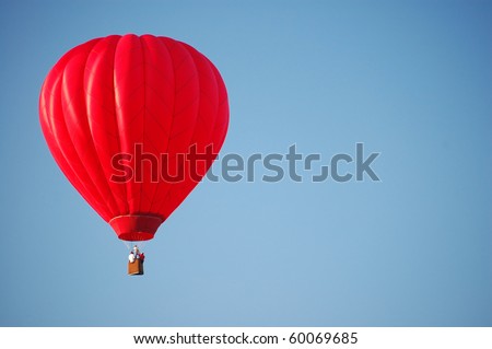 A red hot-air balloon in the sky on a beautiful summer morning.