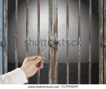 Hand hold key opening locked door with empty space in gray concrete wall background