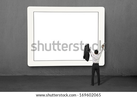 Cheered businessman standing in from of large screen in concrete wall background