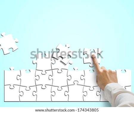 Hand pushing puzzle for assembling in blue background