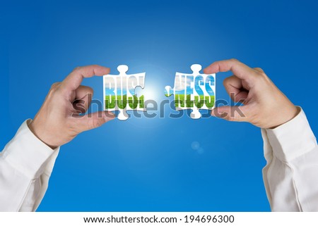 ASsembling two puzzles together for green business blue sky background