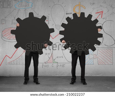 two businessmen holding different gear on concrete floor with doodles wall