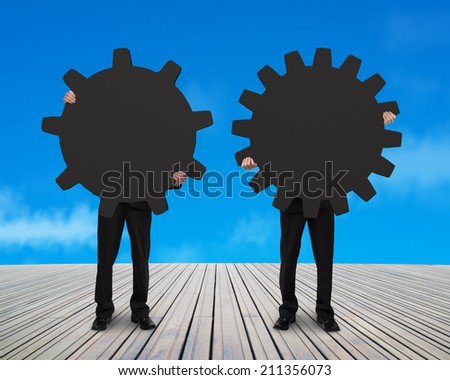 two men holding their different gear on wooden floor with sky background