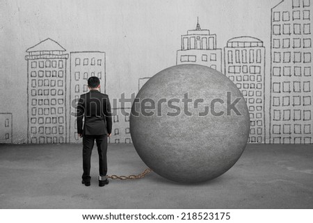 businessman being trapped with concrete ball and doodles wall