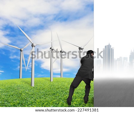 man pushing away city landscape wall with nature sky clouds grass and groups of wind turbines