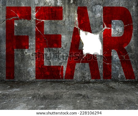 red fear word on old mottled concrete wall with large blank hole, overcoming fear concept.