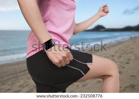 sport female wearing smartwatch with bright pink watchband blank black glass bent touchscreen on natural sea beach background