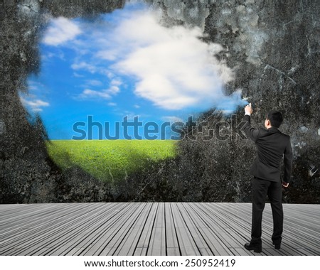 Businessman spraying sky cloud grass paint on dirty concrete wall background