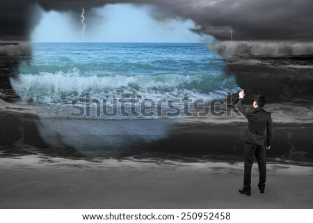 Businessman spraying calm sea paint covered dark stormy ocean background