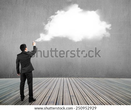 Businessman spraying white cloud paint on gray concrete wall background