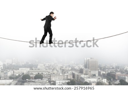 Businessman balancing and walking on the rope high in the sky with urban scene background
